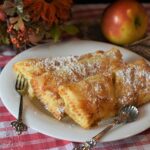 Frittelle di mele al forno dorate su un piatto, decorato con zucchero a velo e fette di mela.