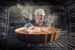 Torta di mele appena sfornata, dorata e soffice, su un piatto decorato, con ricetta della nonna.